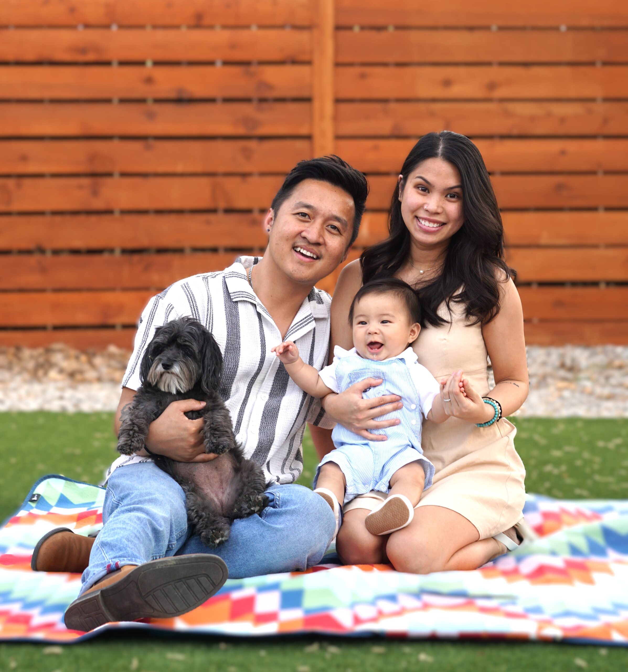 Family with child and pet sitting outdoors in a relaxed outdoor setting